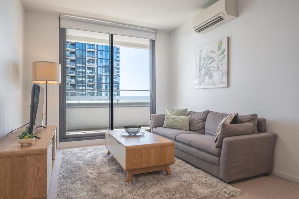 a living room with a couch and a large window at Panoramic Views 2br With Pool And Free Carpark in Melbourne