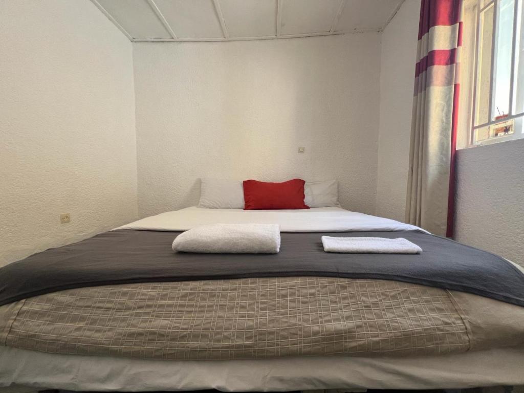 een slaapkamer met een groot bed met een rood kussen bij Eco Escape Home in Ruhengeri