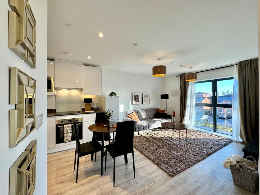 a kitchen and a living room with a table and chairs at Newly built apt in central Derby with on street parking in Derby