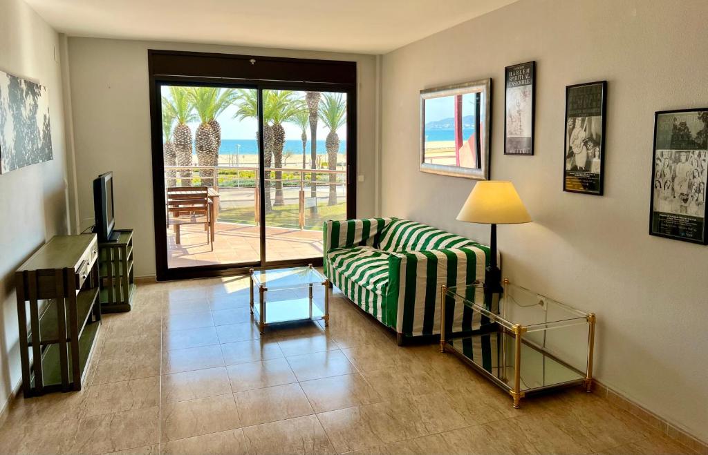 uma sala de estar com um sofá e uma porta de vidro deslizante em Primera Linea Seaview em Empuriabrava