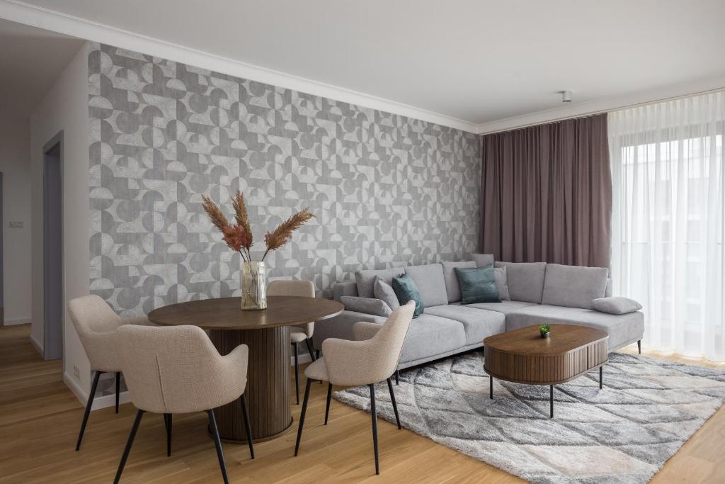 a living room with a couch and a table and chairs at Wilanów Branickiego Deluxe Apartment in Warsaw