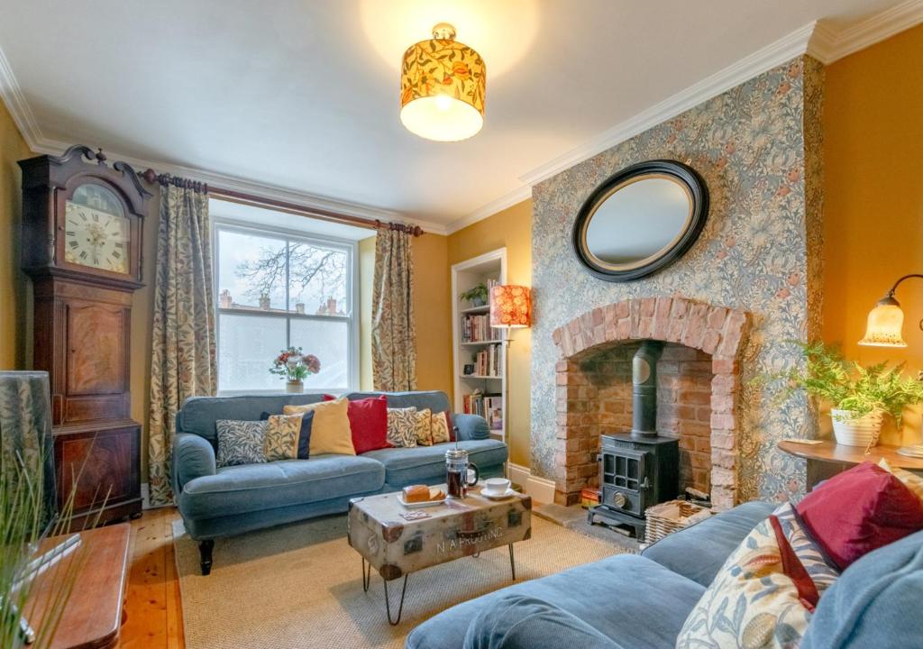 sala de estar con sofá azul y chimenea en Pantile Cottage, en Pickering