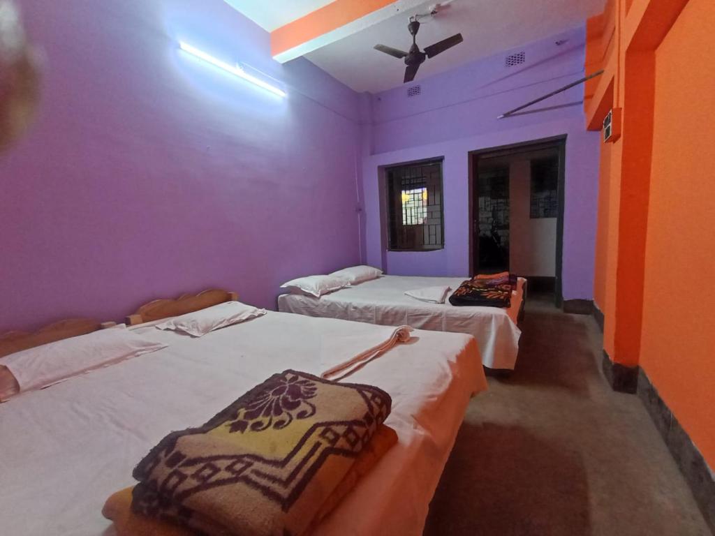 a room with three beds and a ceiling fan at Nona Mati Lodge in Gosāba