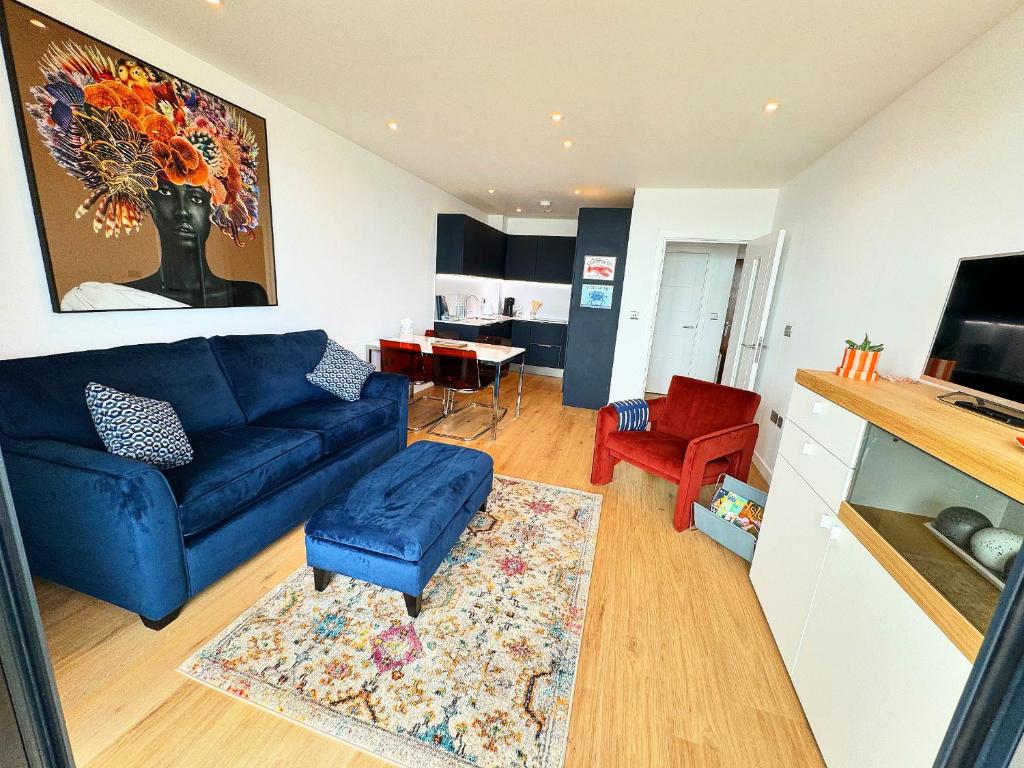 ein Wohnzimmer mit einem blauen Sofa und einem Tisch in der Unterkunft Stunning Beach Front Apartment with Sea views, FREE Parking & Balcony in Ramsgate