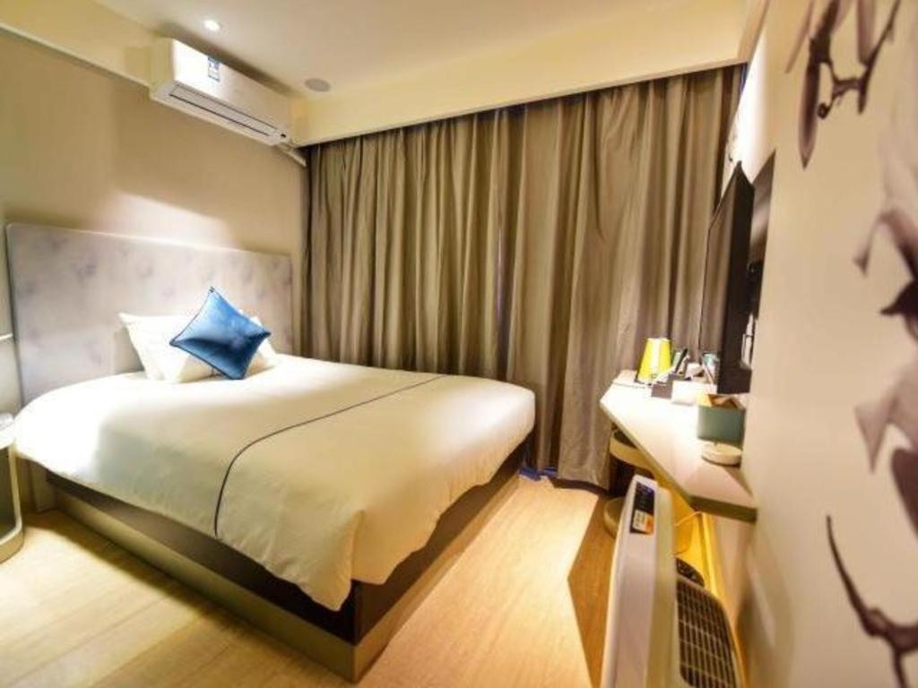 a hotel room with a large bed and a desk at Magnotel Hotel Chengdu Taikoo Li Dongfeng Bridge A in Chengdu