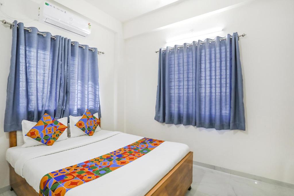 a small bedroom with blue curtains and a bed at FabHotel Blue Ocean MNJ Resort in Nashik