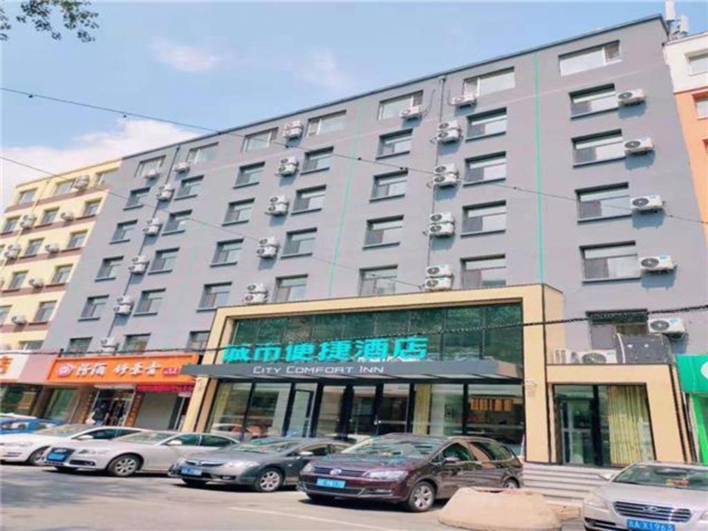 een groot gebouw met auto's geparkeerd voor het bij City Comfort Inn Changchun Wenhua Square Xi Zhonghua Road in Changchun
