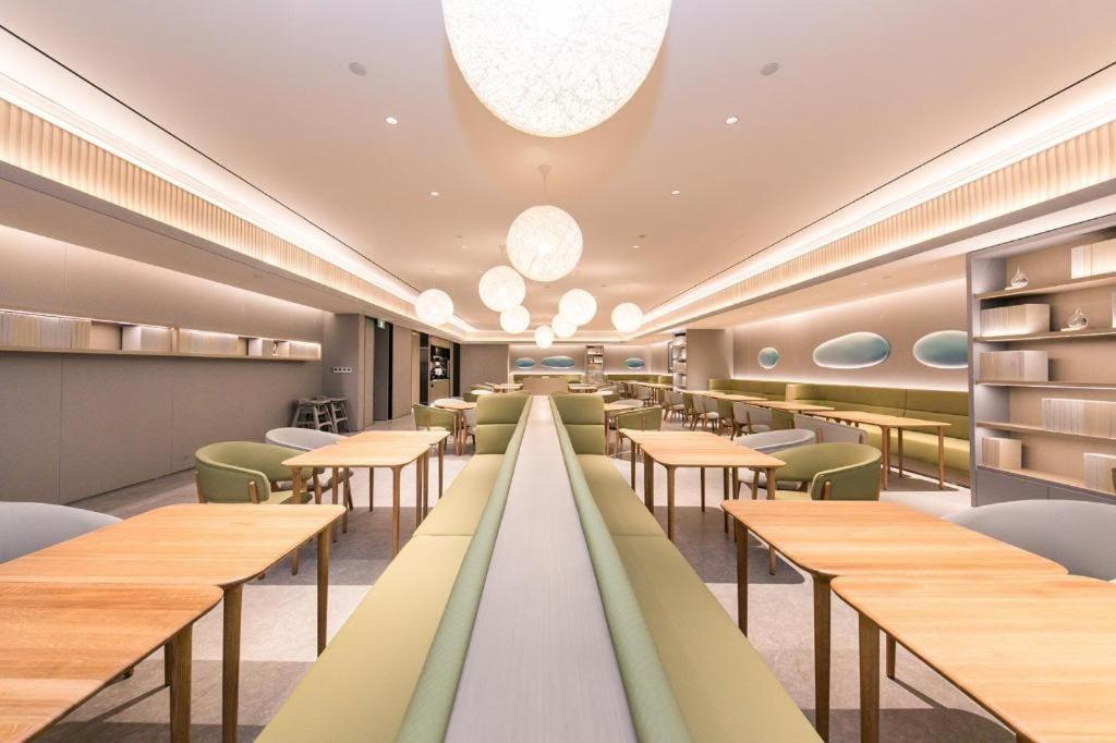 um restaurante com mesas de madeira e cadeiras verdes em JI Hotel Hangzhou Qianjiang New City Civil Center em Hangzhou