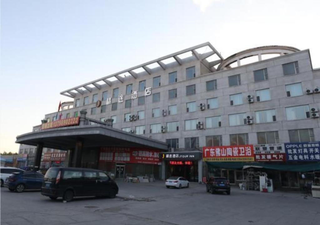 ein großes Gebäude mit Autos auf einem Parkplatz in der Unterkunft JTOUR Inn Qingnian Road Zhubang Plaza Yanming Lake in Changchun