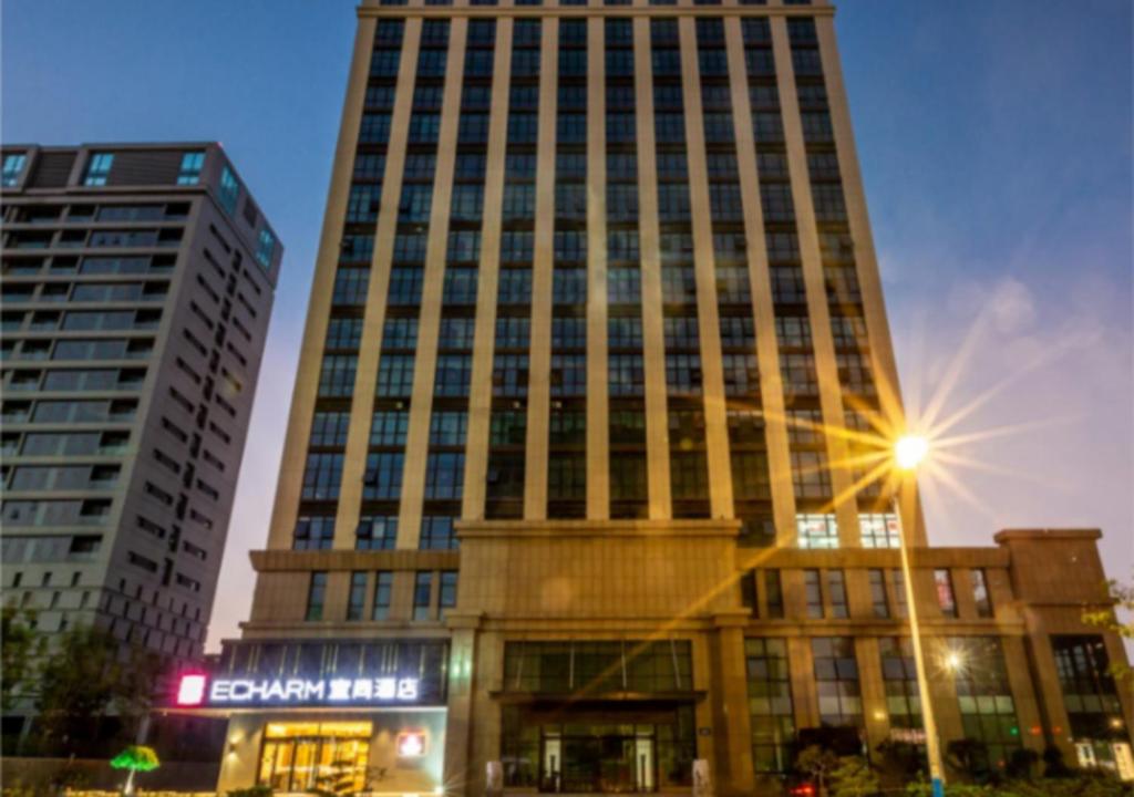 un edificio alto con una luz de la calle delante de él en Echarm Hotel Jiaxing Xiuhu Park Government Center en Jiaxing