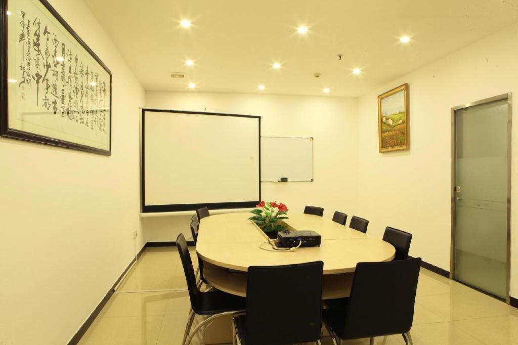 a conference room with a table and chairs and a whiteboard at Hanting Hotel Shenzhen Longgang Nanlian Metro Station in Longgang