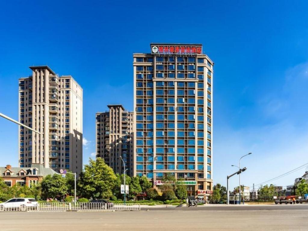 un edificio alto con un cartel en la parte superior en GreenTree Inn Express Kunming East Passenger Station Huazhicheng en Kunming
