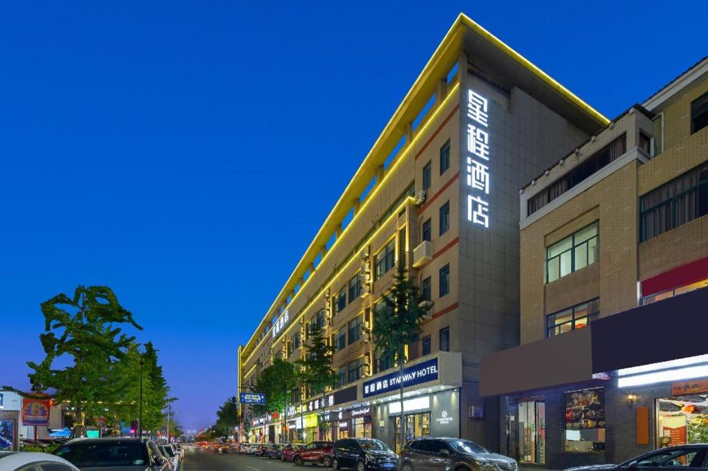 un edificio en una calle con coches aparcados delante en Starway Hotel Hangzhou Yipeng Shopping Center, en Chang-shen-tien