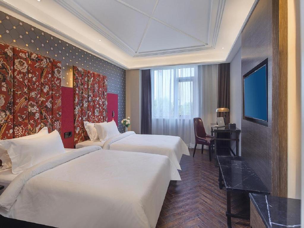 QingxiuにあるHanting Hotel Nanjing Jiangning Binjiang Development Zone Parkのベッド2台とテレビが備わるホテルルームです。