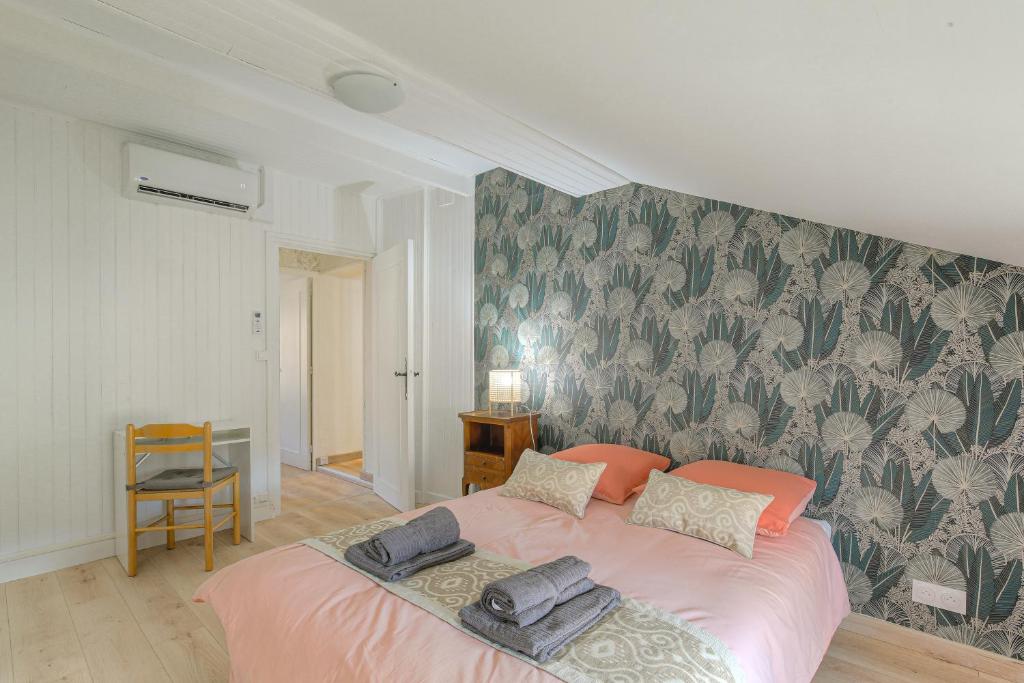 a bedroom with a pink bed with a floral wallpaper at Gîte La Terrasse, 4 chambres, 10 pers, Centre Ville in Lagnieu