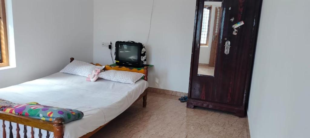 ein Schlafzimmer mit einem Bett und einem TV an der Wand in der Unterkunft VIBGYOR HOME AWAY FROM HOME in Kānnangād