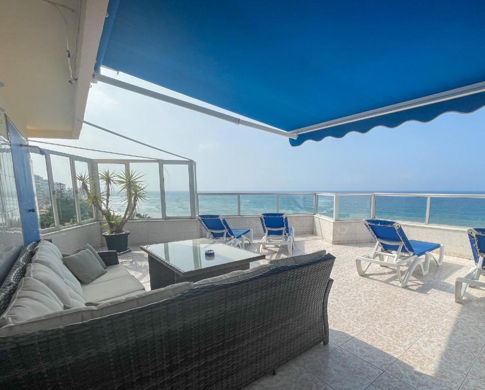 een woonkamer met een bank en stoelen en de oceaan bij Ático Alegría Del Mar in Torrox Costa