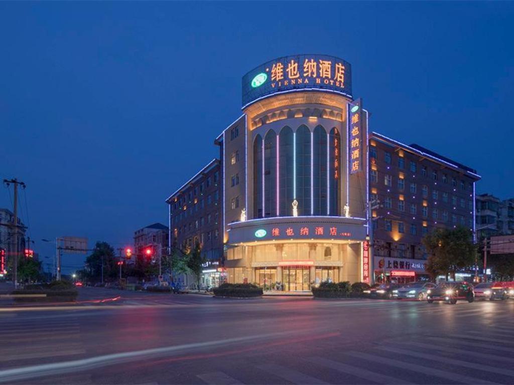 Vienna Hotel Jiangxi Shangrao Yiyang Railway Station Fangzhimin Avenue في Yiyang: مبنى عليه علامة في الليل