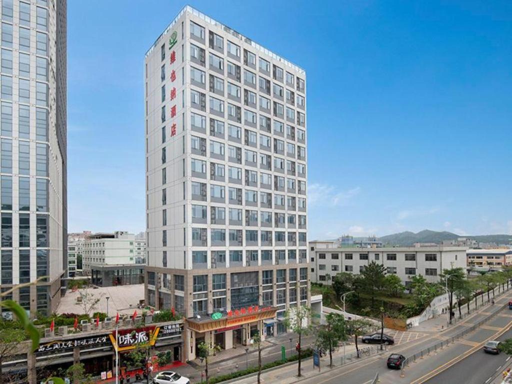 un edificio alto y blanco en medio de una ciudad en Vienna Hotel Shenzhen Henggang Metro Station en Bingkeng