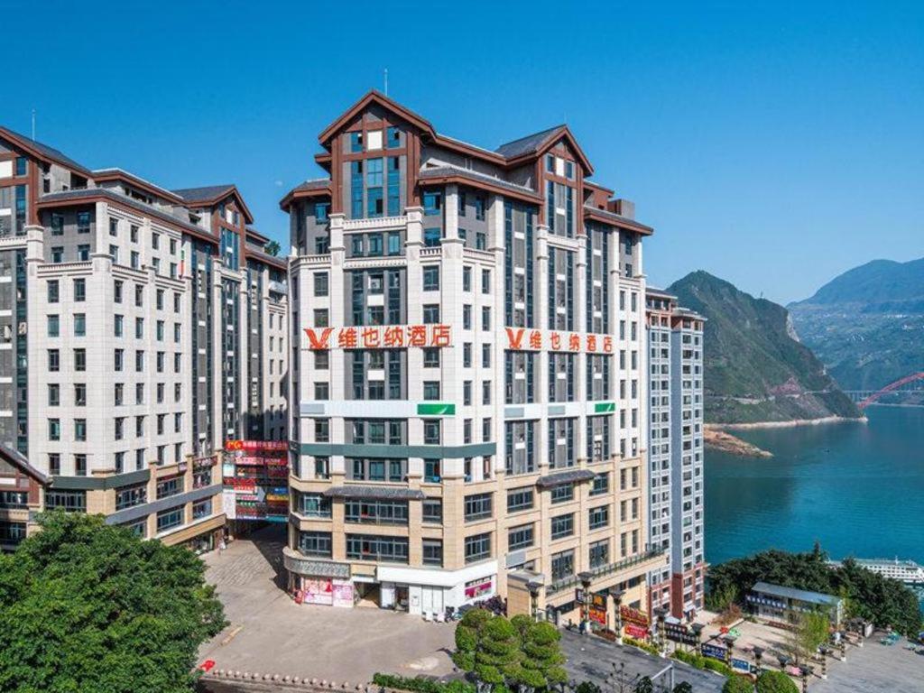 a large white building next to a body of water at Vienna Hotel Chongqing Wushan Municipal Government in Wushan