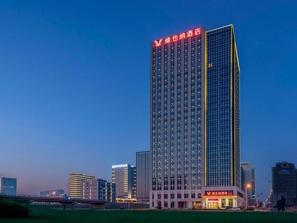 a tall building with a sign on top of it at Vienna Hotel Tianjin Binhai New District Ocean High-Tech Zone in Binhai