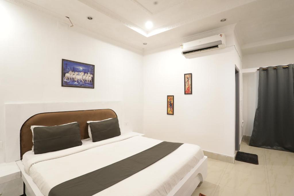 a bedroom with a bed in a white room at Goroomgo Hotel Hi5 Stay Near Care Hospital in Bhubaneshwar