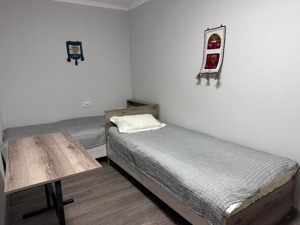 a room with two beds and a table in it at Holy Moly Hostel in Bishkek