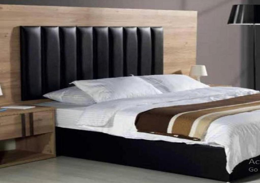 a bedroom with a large bed with a black headboard at دار ياقوت للشقق المفروشة in Obhor