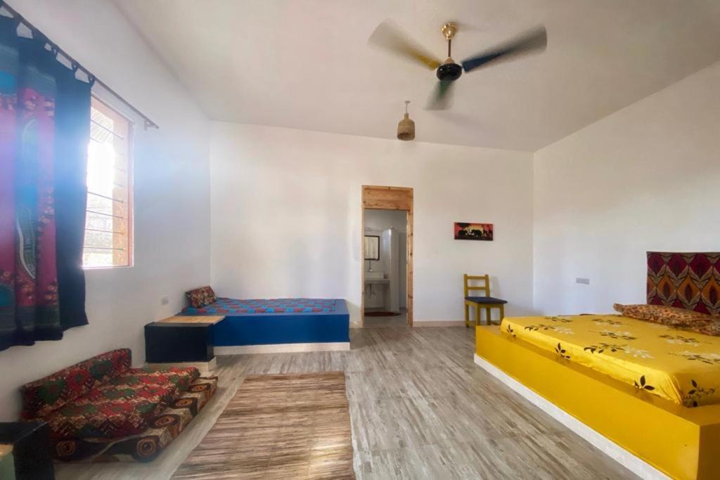 ケンドワにあるZanzibat bungalowのベッド2台とソファが備わる客室です。