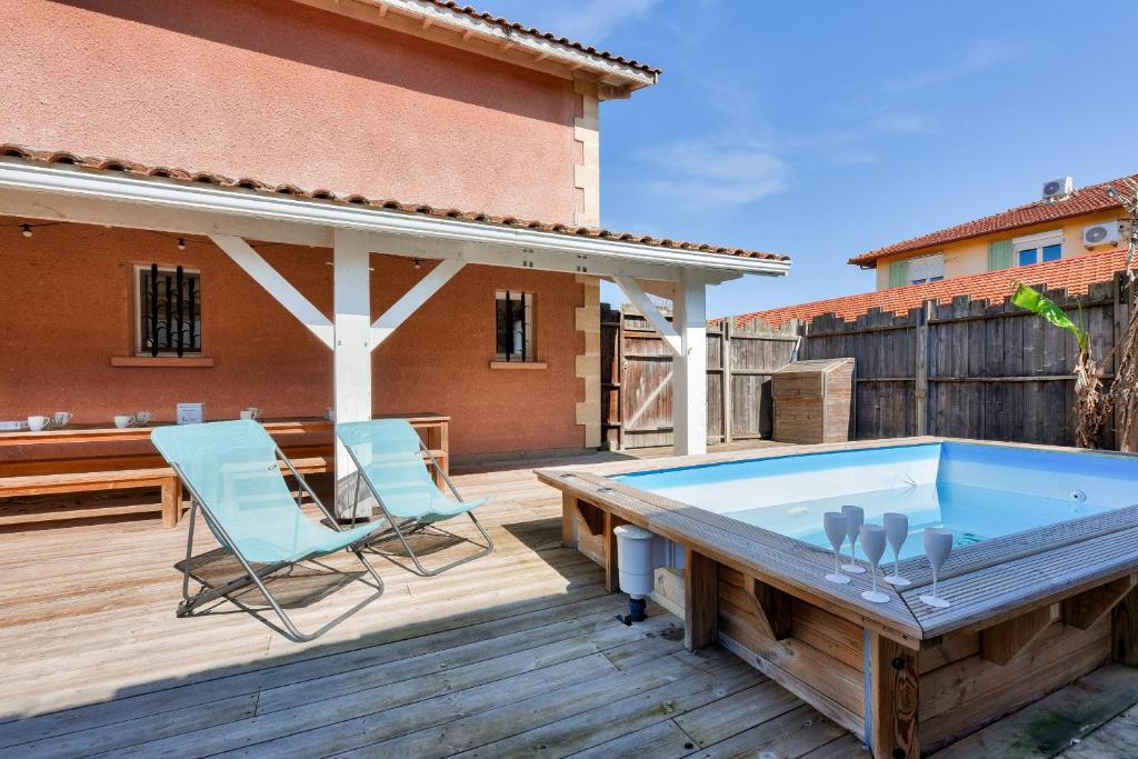 a hot tub on a deck with two chairs at 950m de la plage - Maison pour 10 avec piscine in Arès