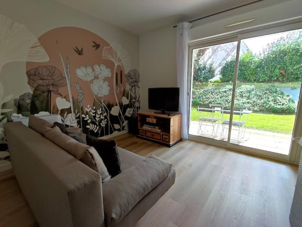 - un salon avec un canapé et une grande porte coulissante en verre dans l'établissement Appartement avec WIFI, terrasse, jardin à TREBEURDEN Réf - 678, à Trébeurden