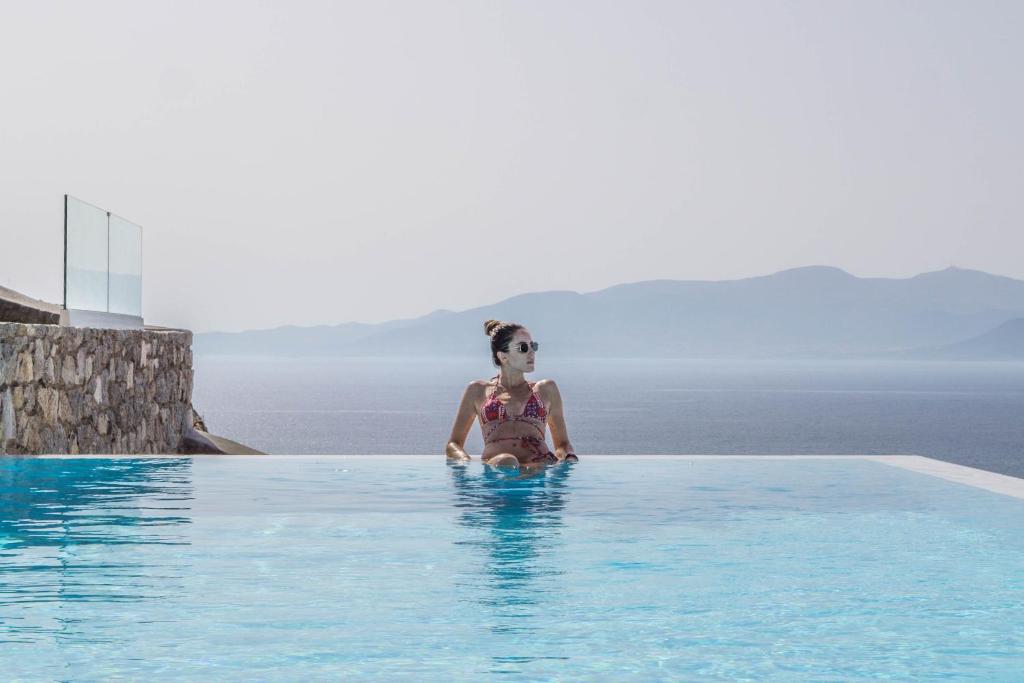 a woman sitting in a swimming pool at Bellevue Villas in Plaka