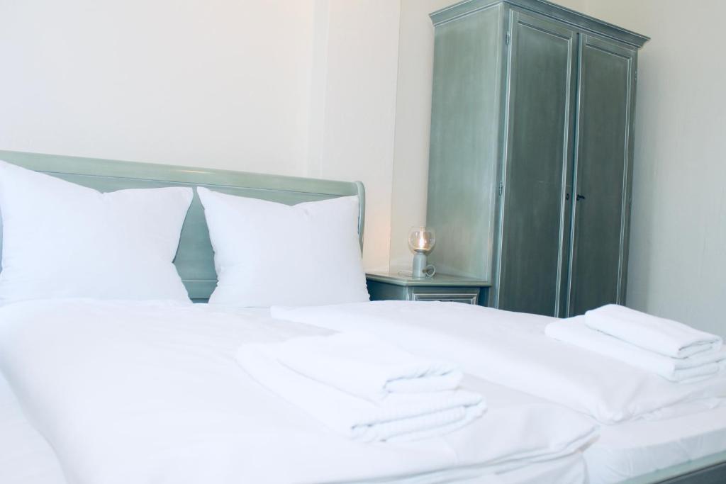 1 dormitorio con 1 cama blanca y armario verde en FREVOR Hotel & Restaurant Alte Wassermühle Lenzen Elbe, en Lenzen