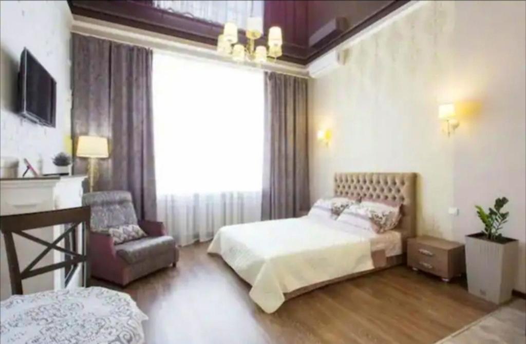 ein Schlafzimmer mit einem Bett, einem Stuhl und einem Fenster in der Unterkunft Studio on Rymarskaya in Kharkov