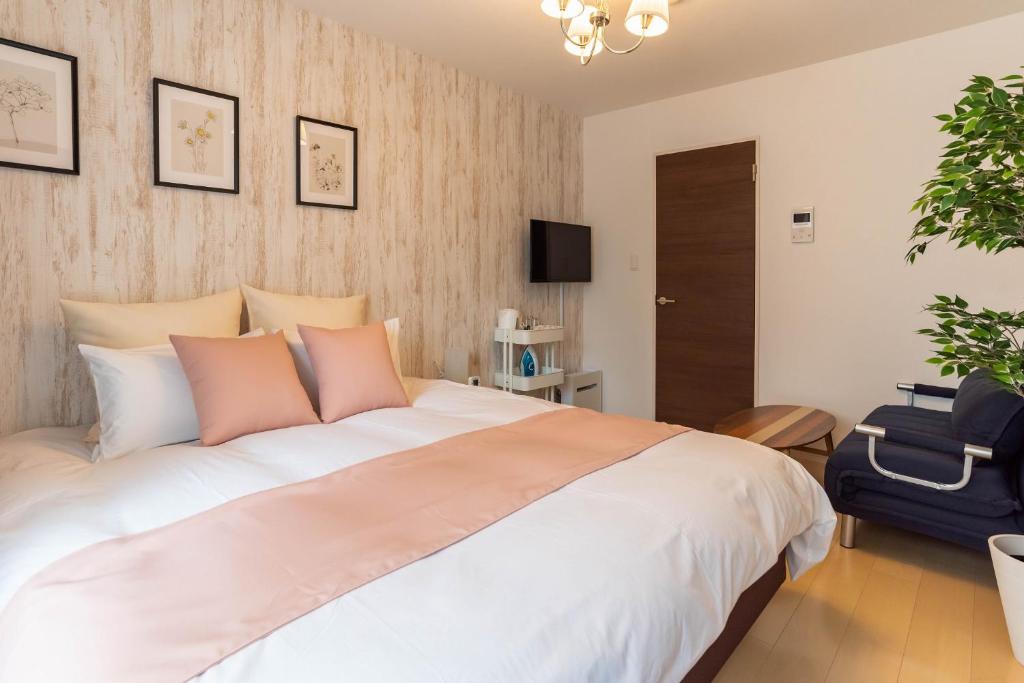 a bedroom with a large white bed with pink pillows at FDS Liberta in Osaka
