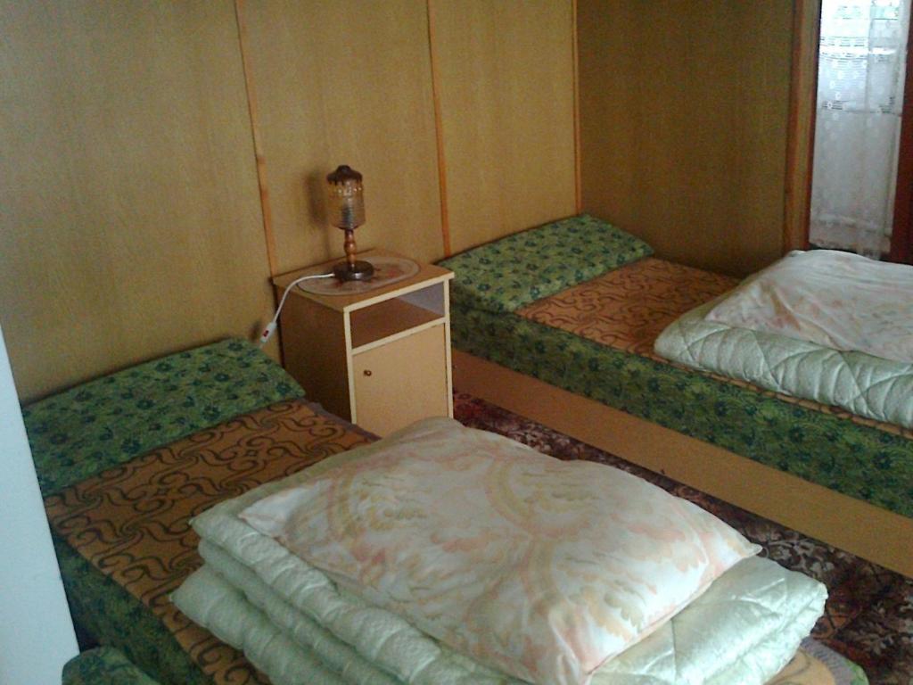 Cette chambre comprend deux lits et une table avec une lampe. dans l'établissement Maxim Pokoje Gościnne, à Iwonicz-Zdrój