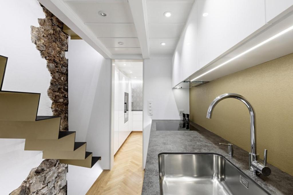 Una cocina con fregadero y una pared de piedra. en Little Escape House with Sauna & perfect Location, en Thun