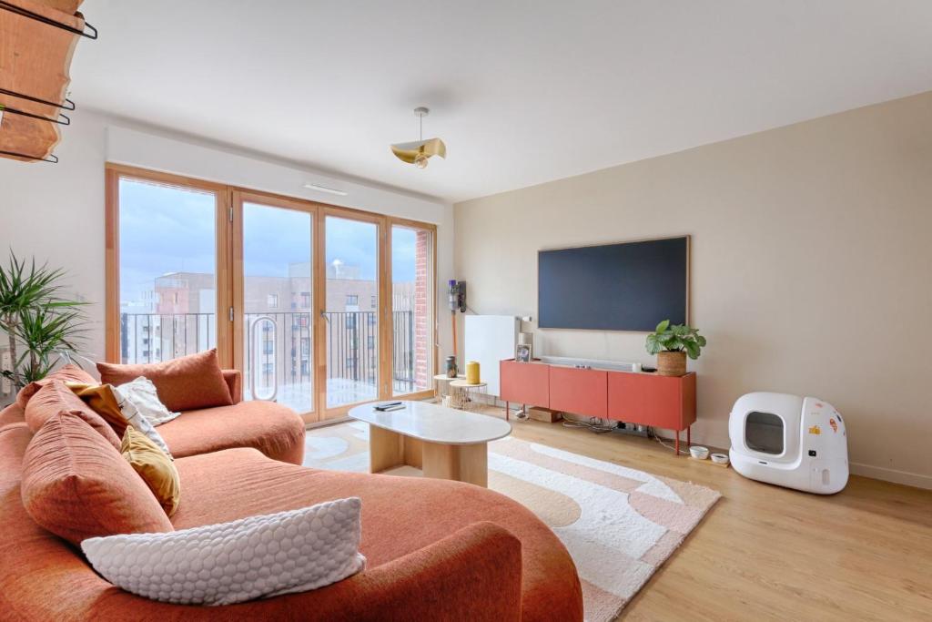 uma sala de estar com um sofá e uma televisão de ecrã plano em Résidor - Sublime Bright Apartment em Asnières-sur-Seine