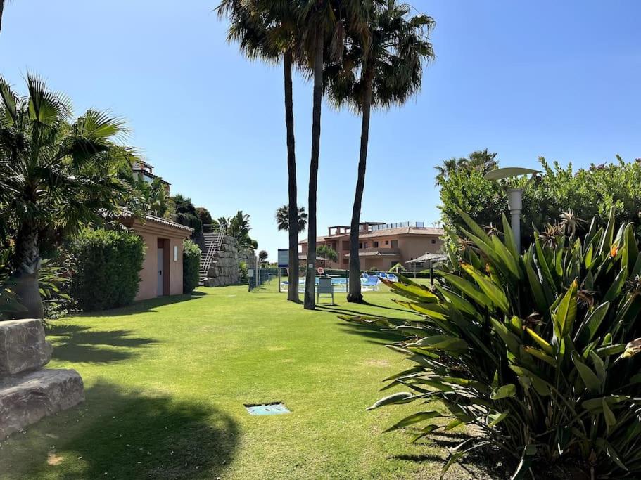 ein grüner Hof mit Palmen und einem Gebäude in der Unterkunft Beautiful apartment,3 min drive from the beach in Bahia de Casares
