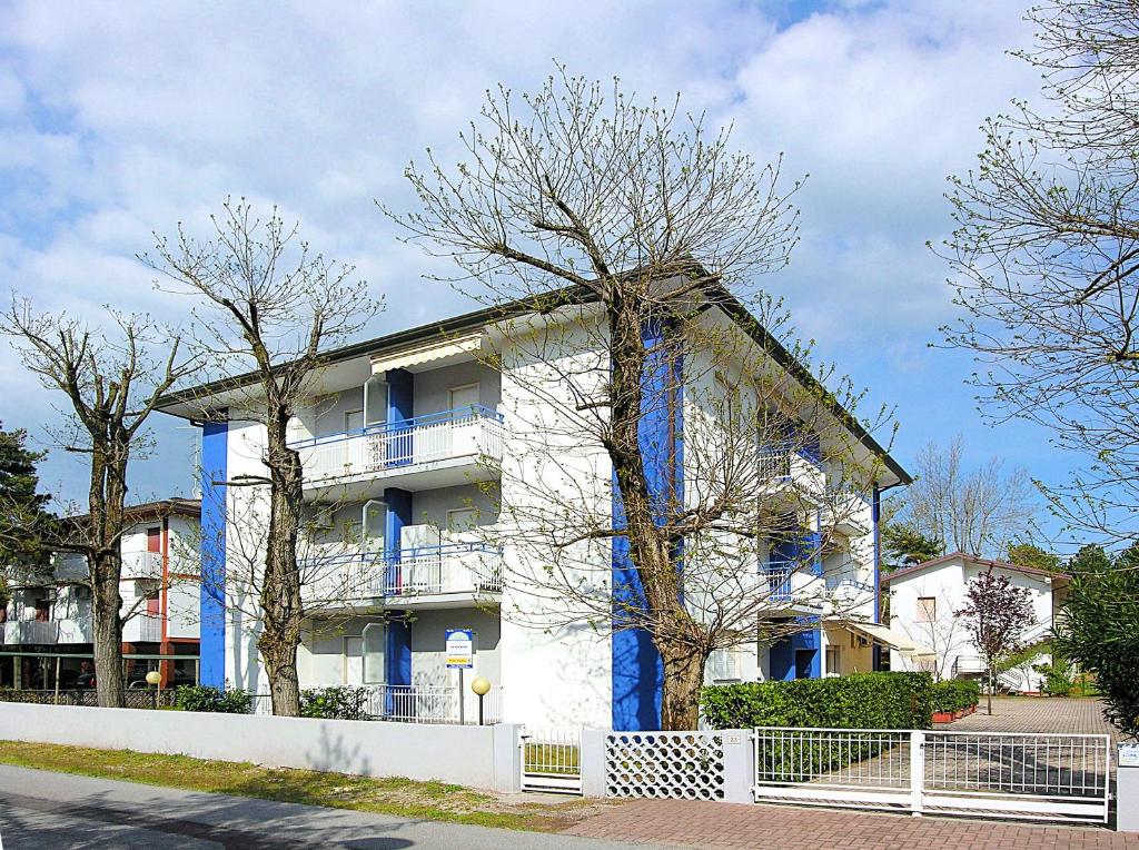 a white building with blue windows and trees at Appartamenti Paola in Bibione