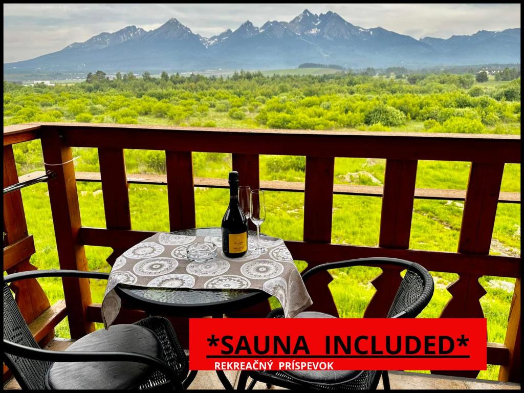 a table with a bottle of wine sitting on a balcony at Tatry PANORAMA apartmány Tatragolf B-F in Veľká Lomnica