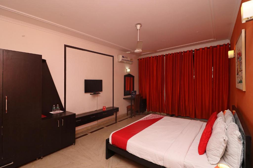 a bedroom with a bed and a red curtain at Flagship RK Residency in Sohāna