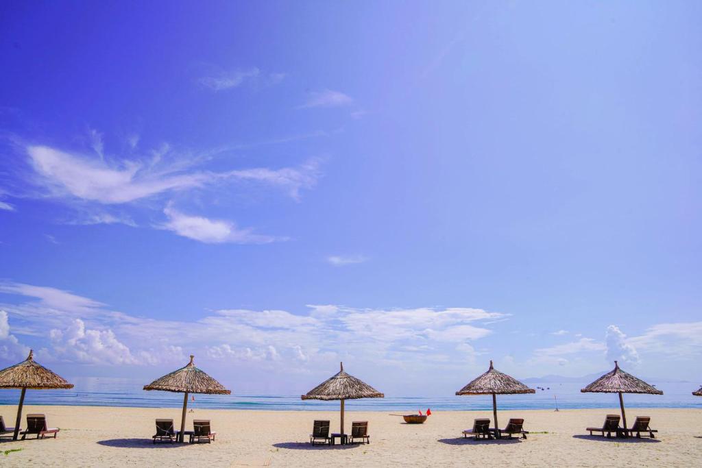 a group of chairs and umbrellas on a beach at Grandvrio Ocean Resort Danang in Hoi An