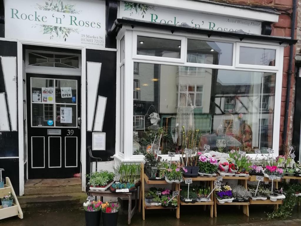 a flower shop with potted plants in the window at The Apartment of Antiquity in Kirkby Stephen
