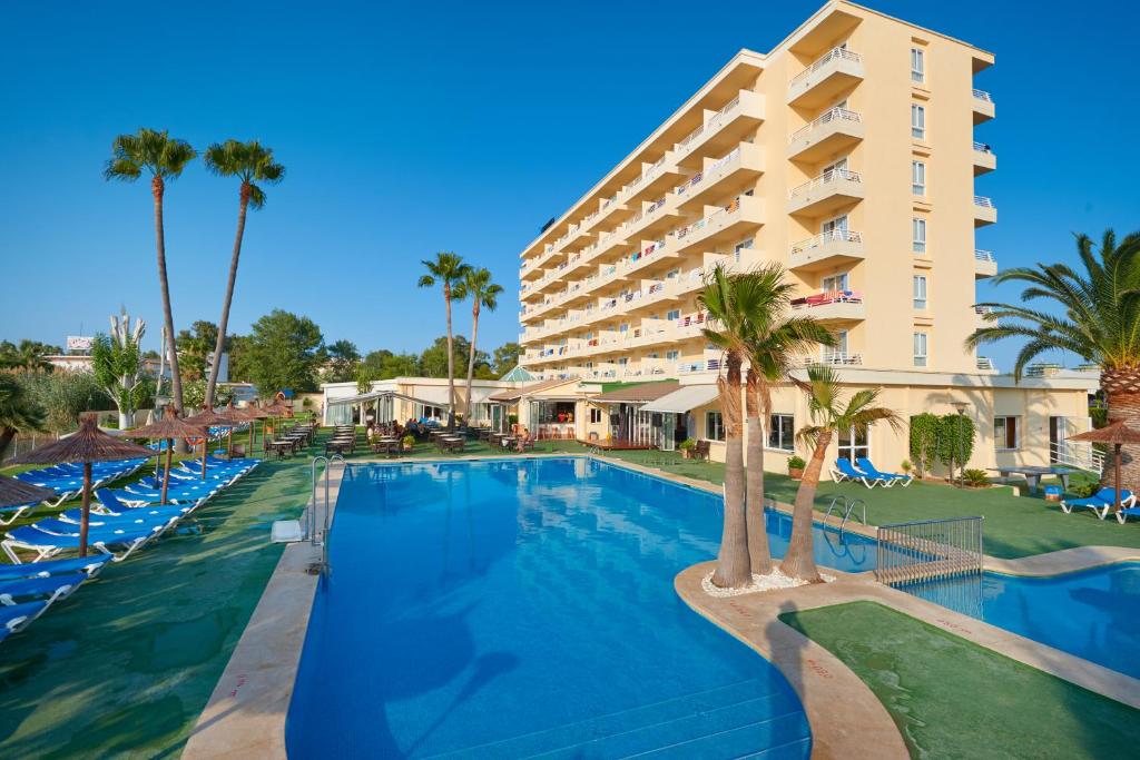 un complejo con una gran piscina y palmeras en Grupotel Amapola en Playa de Muro