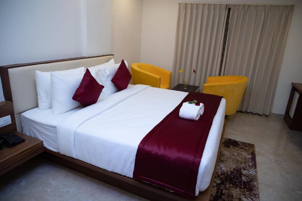 1 dormitorio con 1 cama blanca grande con almohadas rojas en ZIONS AIRPORT HOTEL AND APERTMENT! Near Kempegowda International Airport, en Bangalore