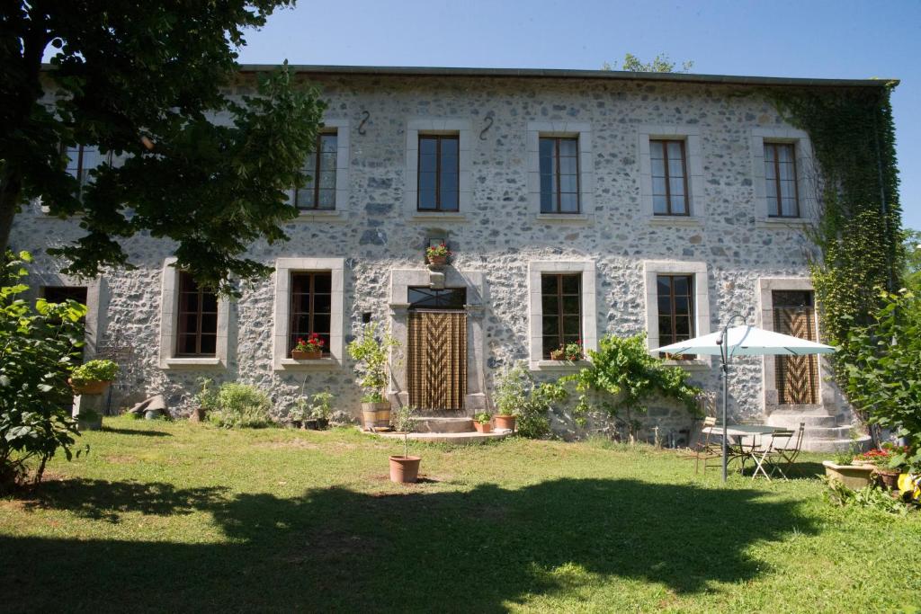 una antigua casa de piedra con una mesa y una sombrilla en Les Ondines, en Gembrie