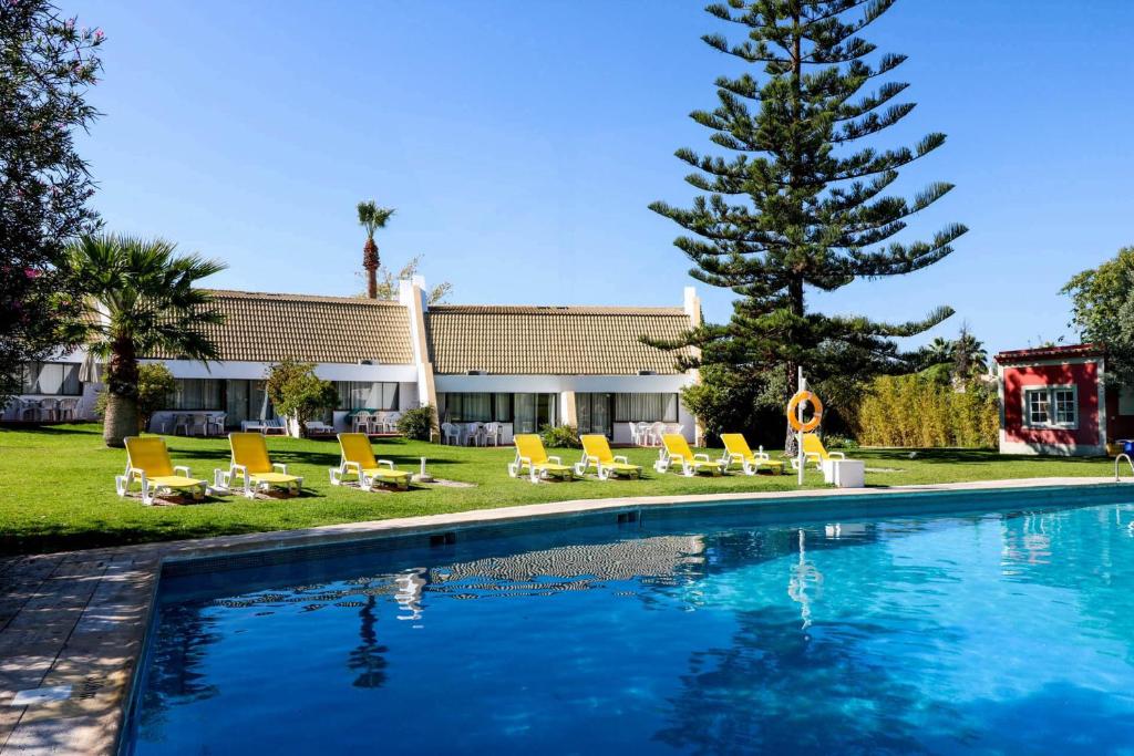 a swimming pool with chairs and a palm tree at Casa Moura Golfe in Vilamoura