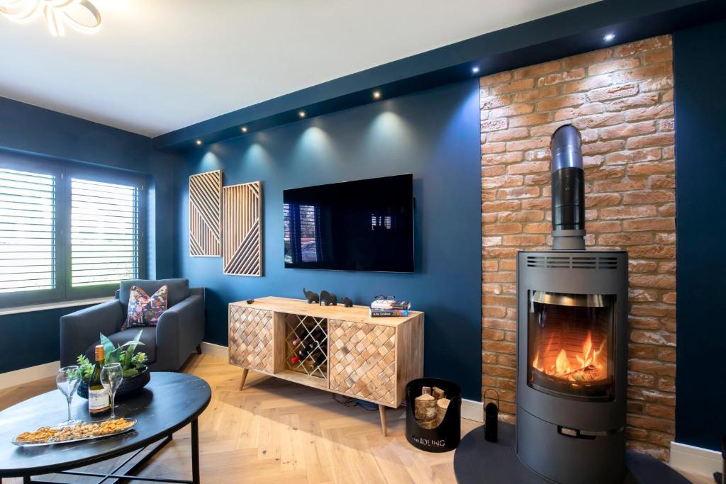 uma sala de estar com lareira e televisão em Elliot Oliver - Superior 6 Bedroom House in Cheltenham With Hot Tub & Log Burner em Cheltenham