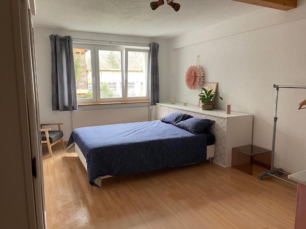 a bedroom with a bed with a blue comforter and a window at Les Rossets in Boudry